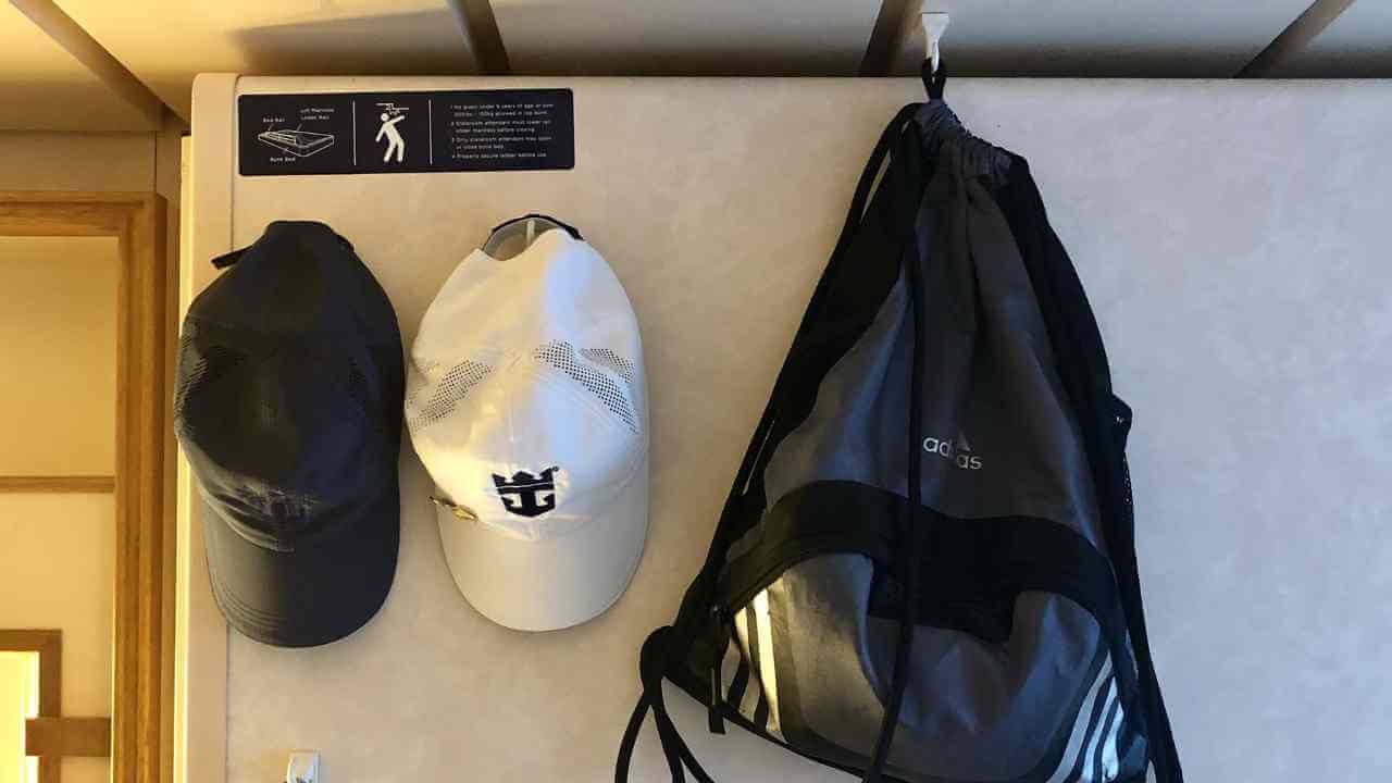 two hats and a backpack hanging on a wall