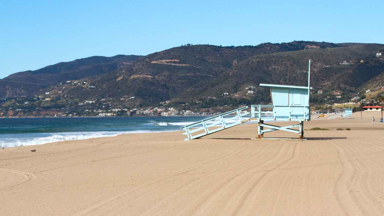 a lifeguard tower on the beach with mountains in the background