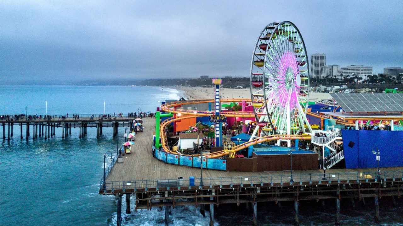 an aerial view of a ferris wheel on a pier next to the ocean