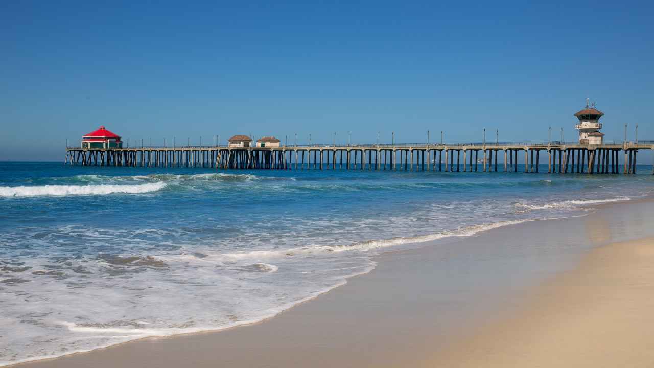 a beach with a pier and waves in front of it