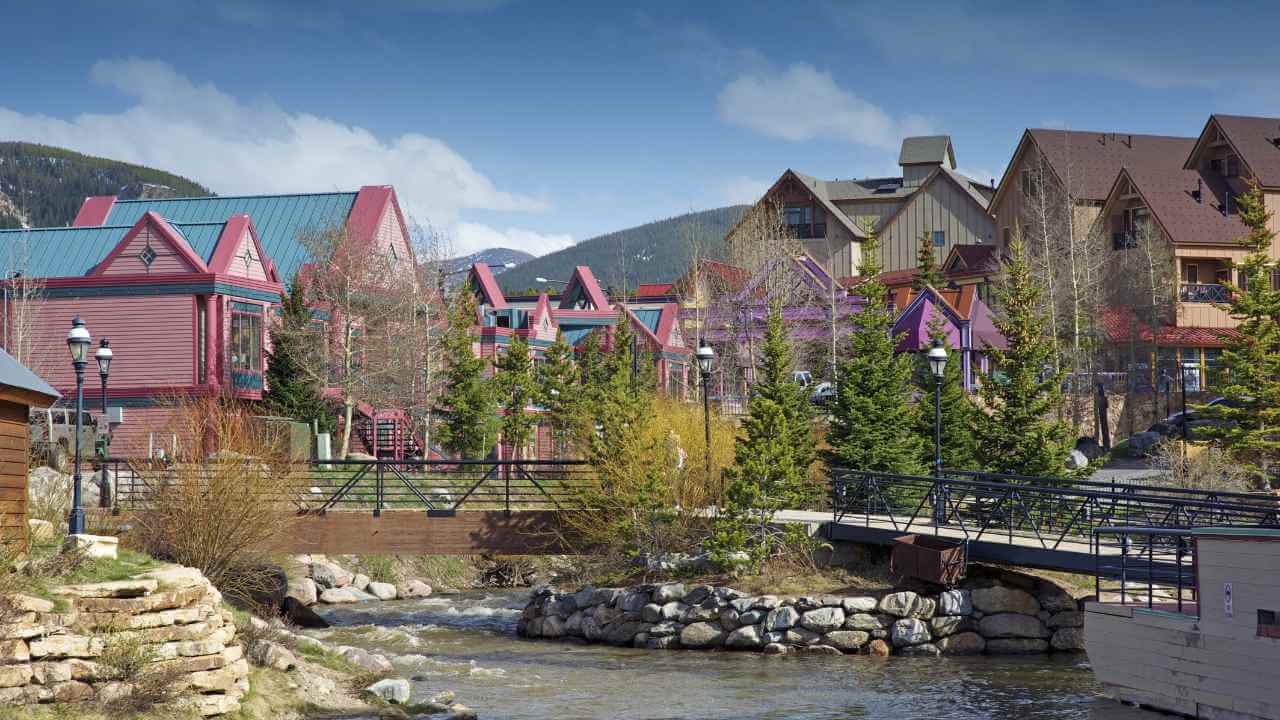 colorful buildings line the banks of a stream in the mountains