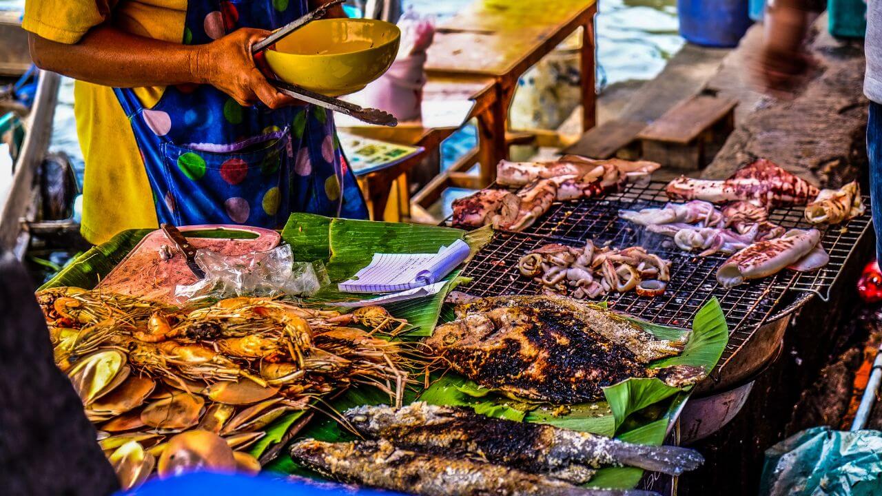 a person is preparing food on a grill at an outdoor market