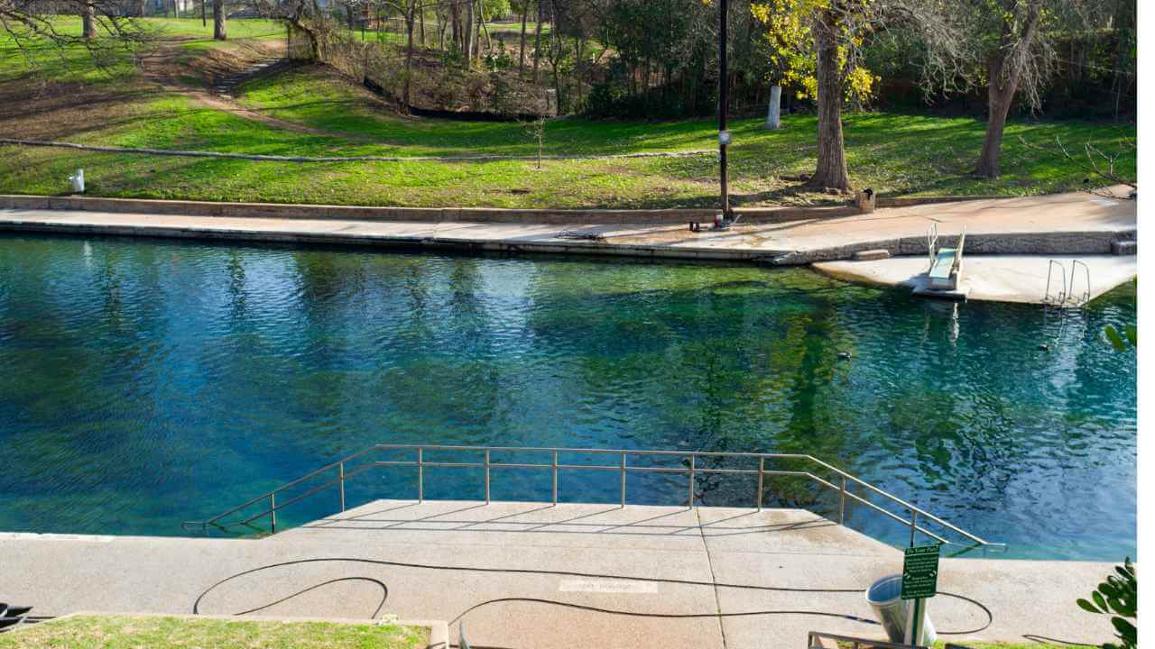 a person is standing on the edge of a pool in a park