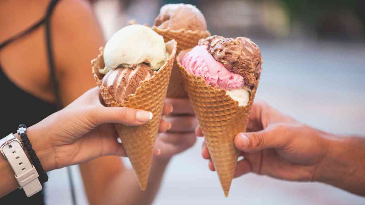 three people holding ice cream cones in front of each other