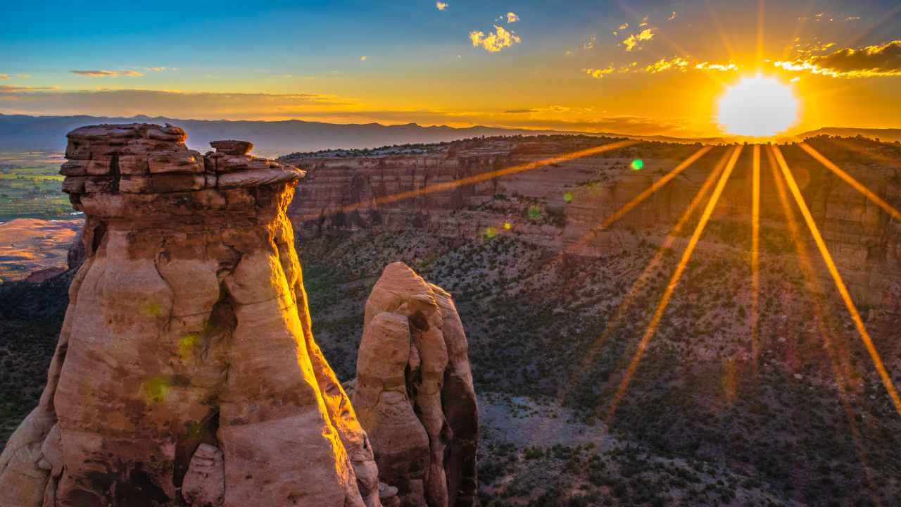 the sun rises over a rock formation in the desert