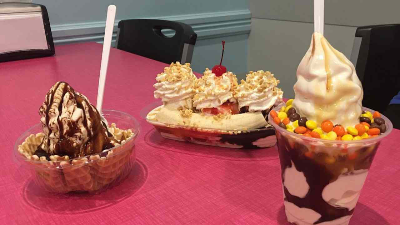 three ice cream sundaes sit on a pink table