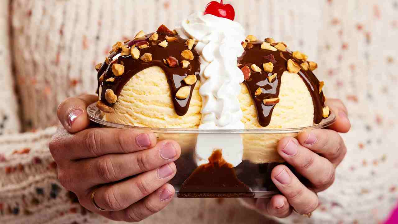 a person holding an ice cream sundae in their hands