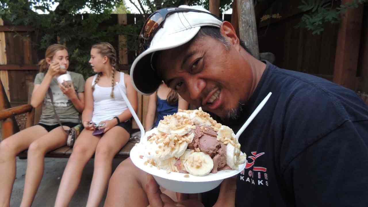 a person sitting on a bench eating an ice cream sundae