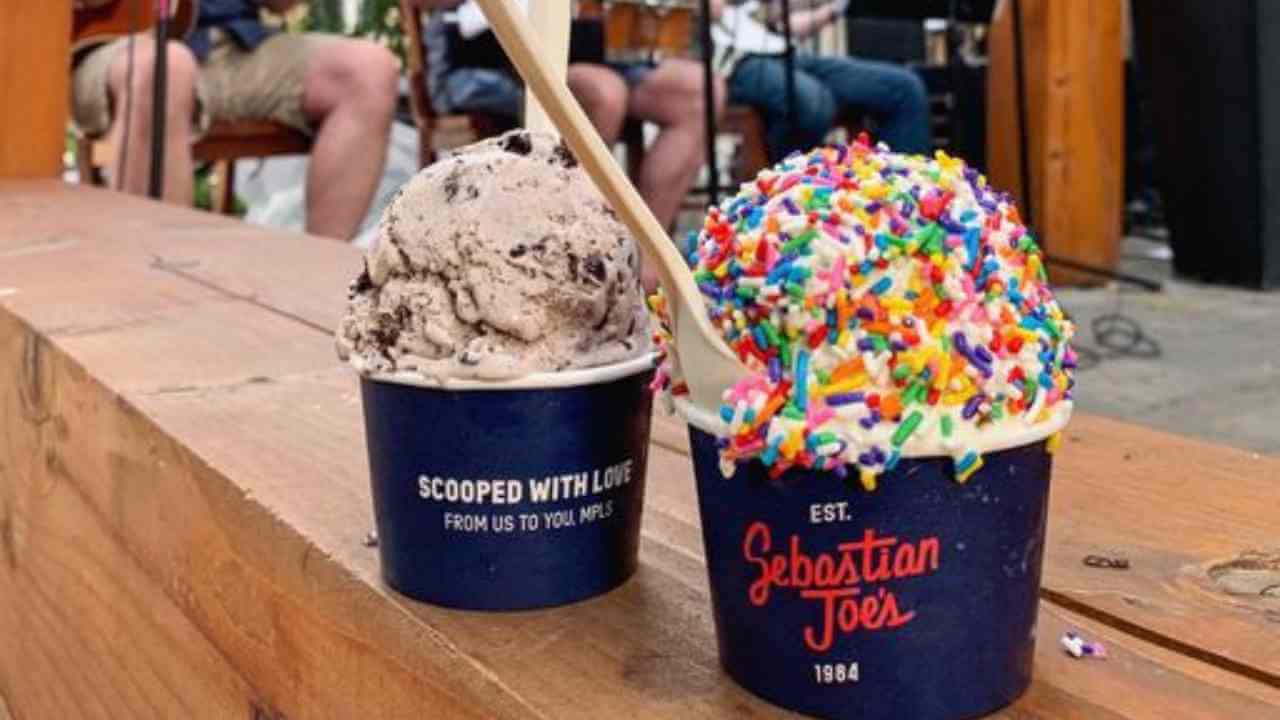 two cups of ice cream with sprinkles sitting on a wooden table