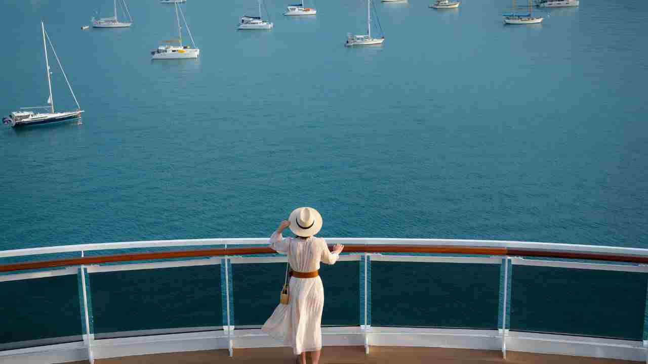 a person in a white dress stands on the deck of a cruise ship