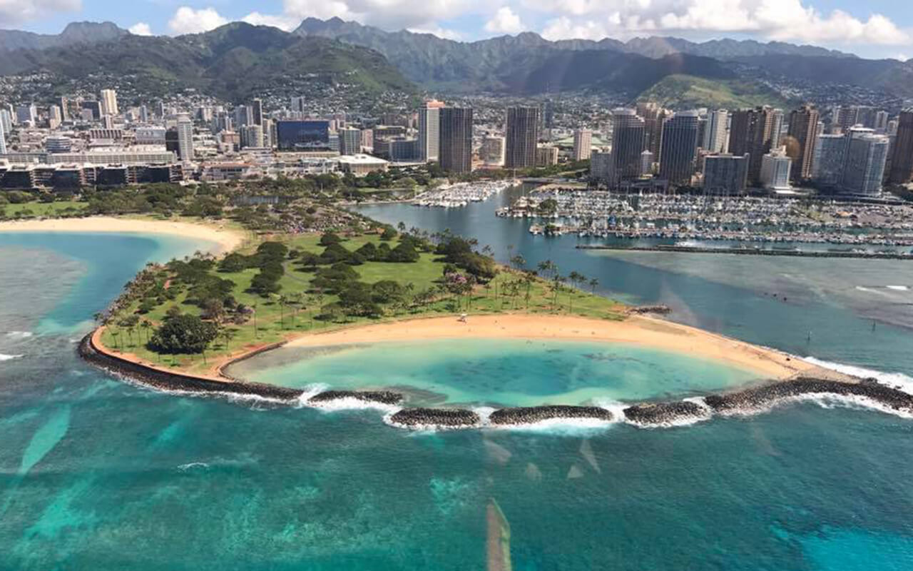This picture is of part of the island Oahu in Hawaii. It was taken on a helicopter ride and shows part of the city and a beach.
