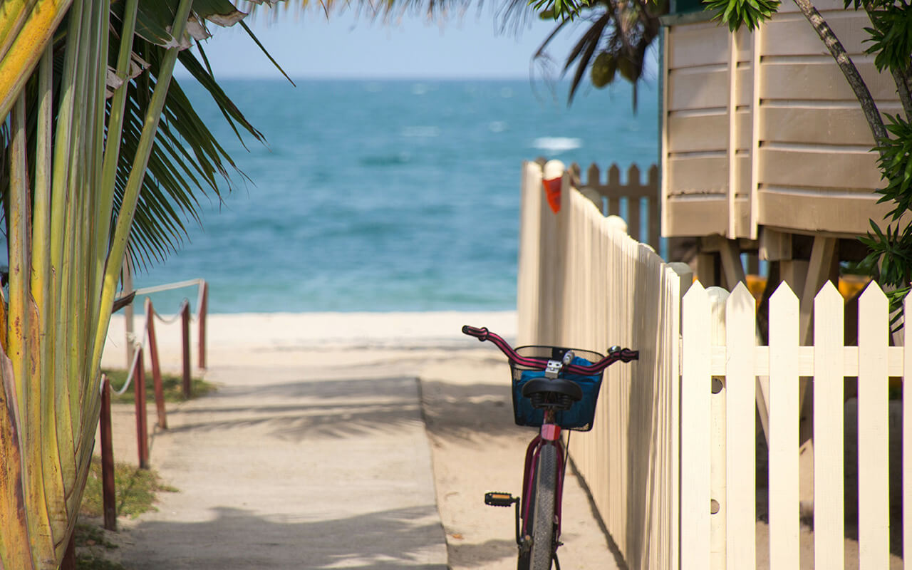 Key West, Florida: A cute beach bicycle rests against a beach house fence, facing the sea and a sandy beach somewhere in the Florida Keys. 