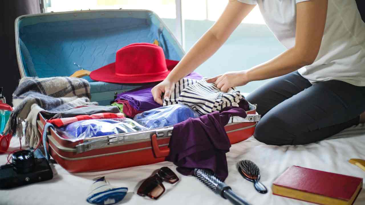 a person sitting on a bed with an open suitcase