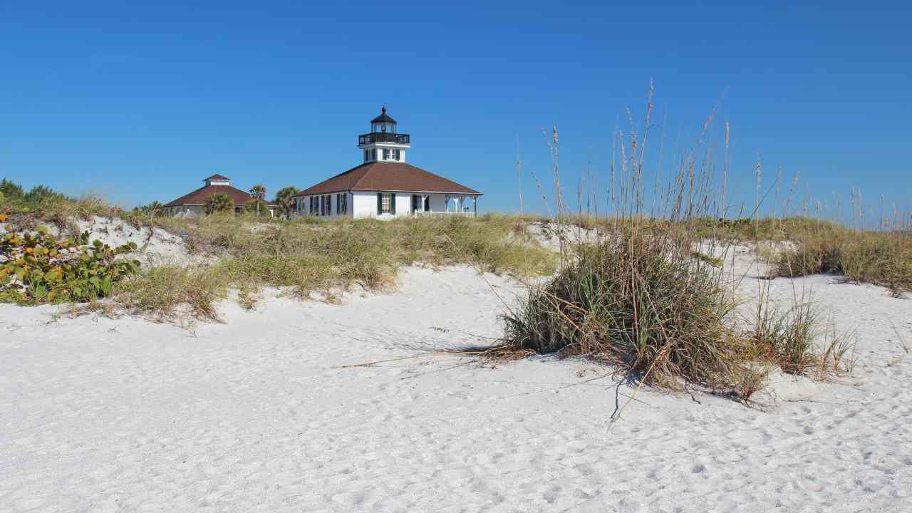 a lighthouse sits on top of a sandy beach