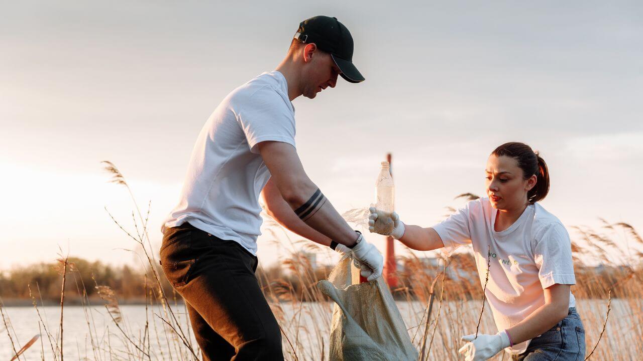 Two people are picking up trash in a field