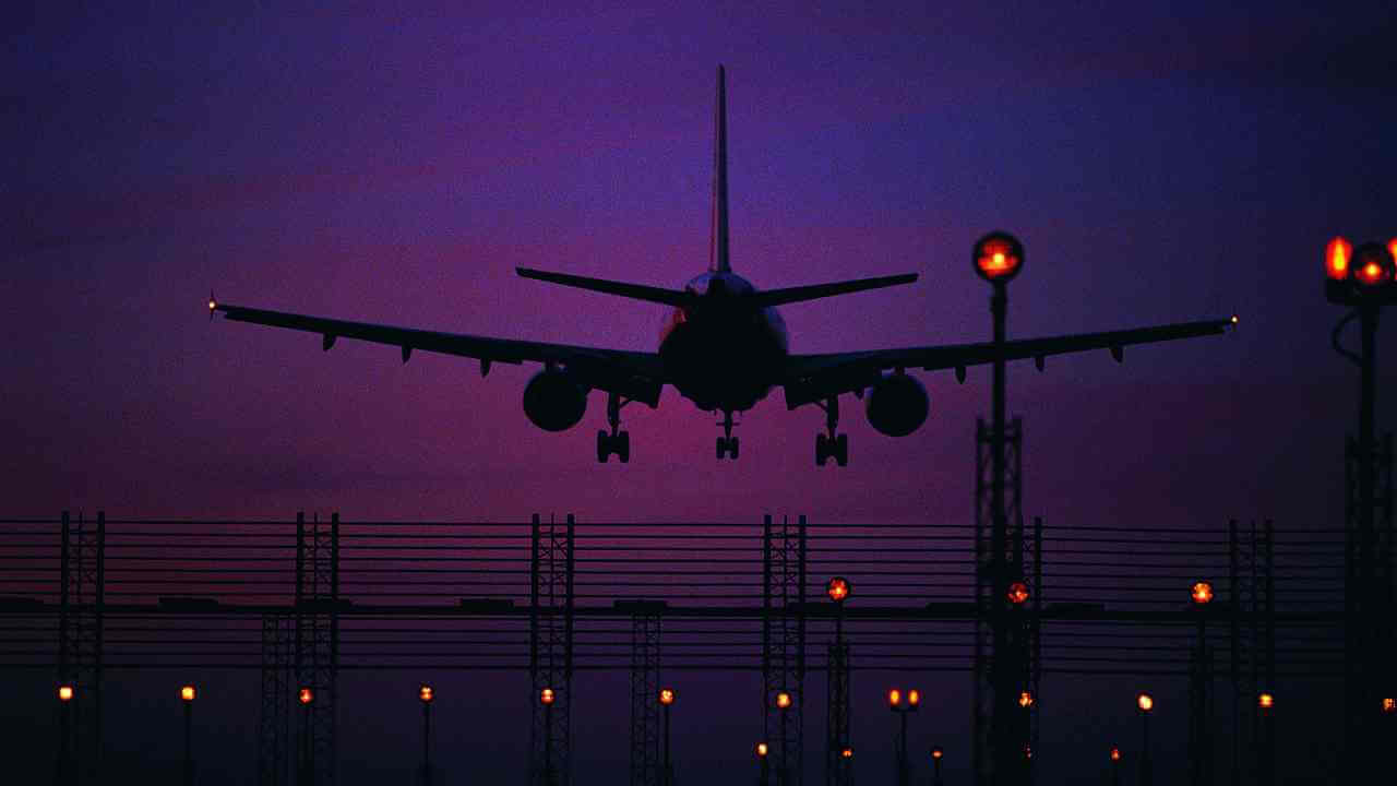 an airplane is taking off at dusk at an airport