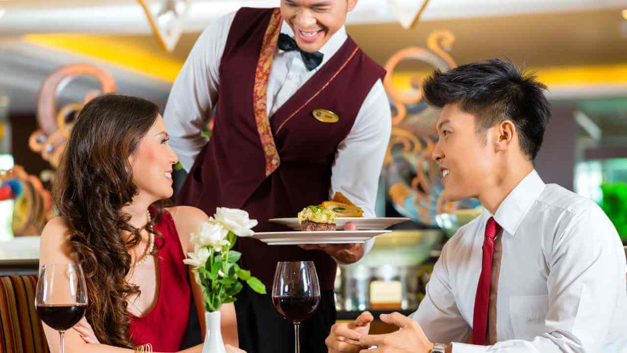 a waiter serving a couple in a restaurant