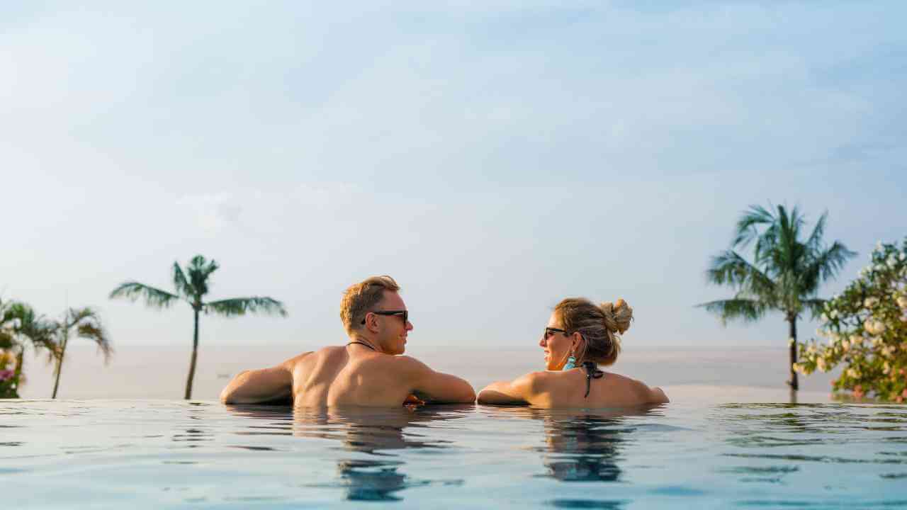 A couple relaxing in swimming pool with palm trees