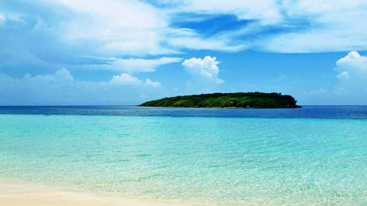 an island in the middle of the ocean with clear water