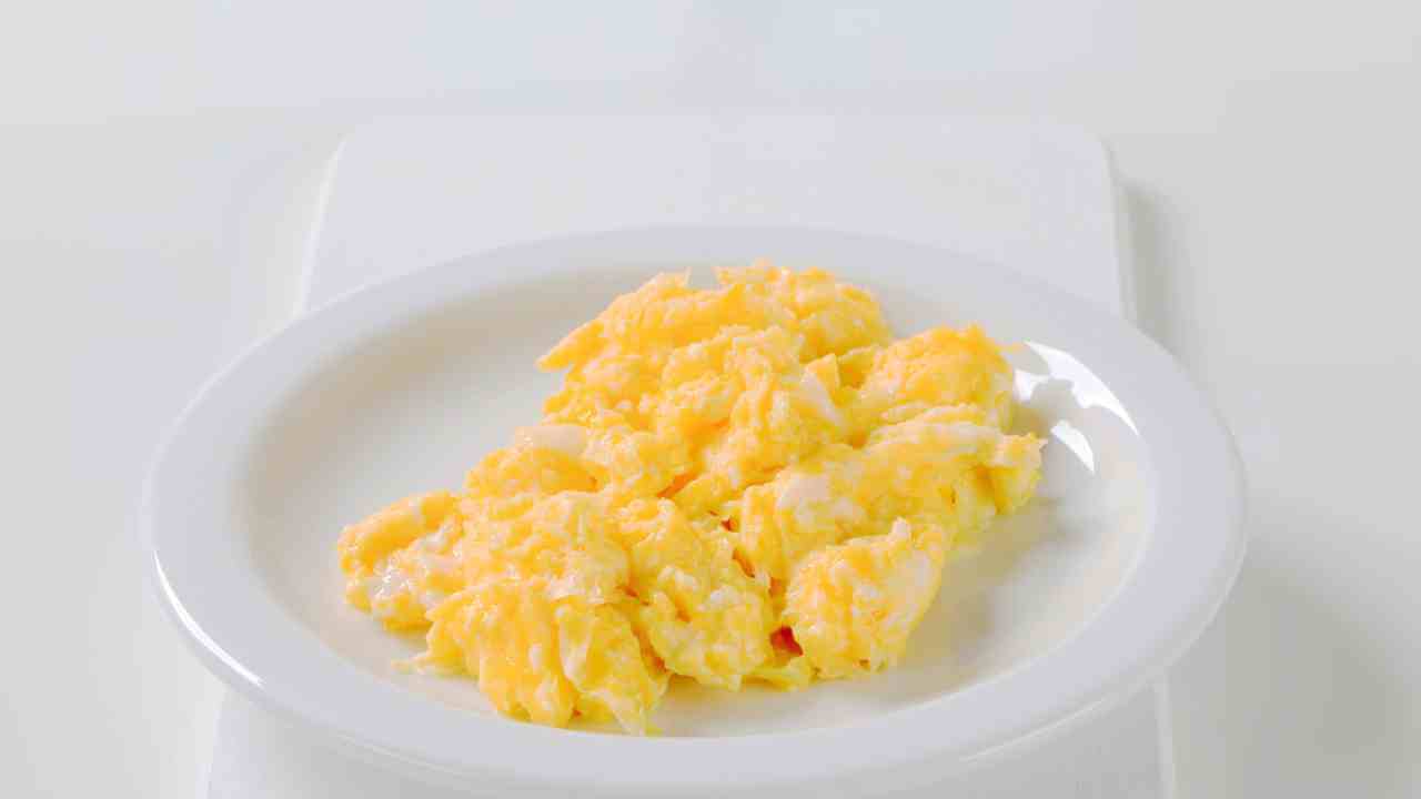 scrambled eggs in a white bowl on a cutting board