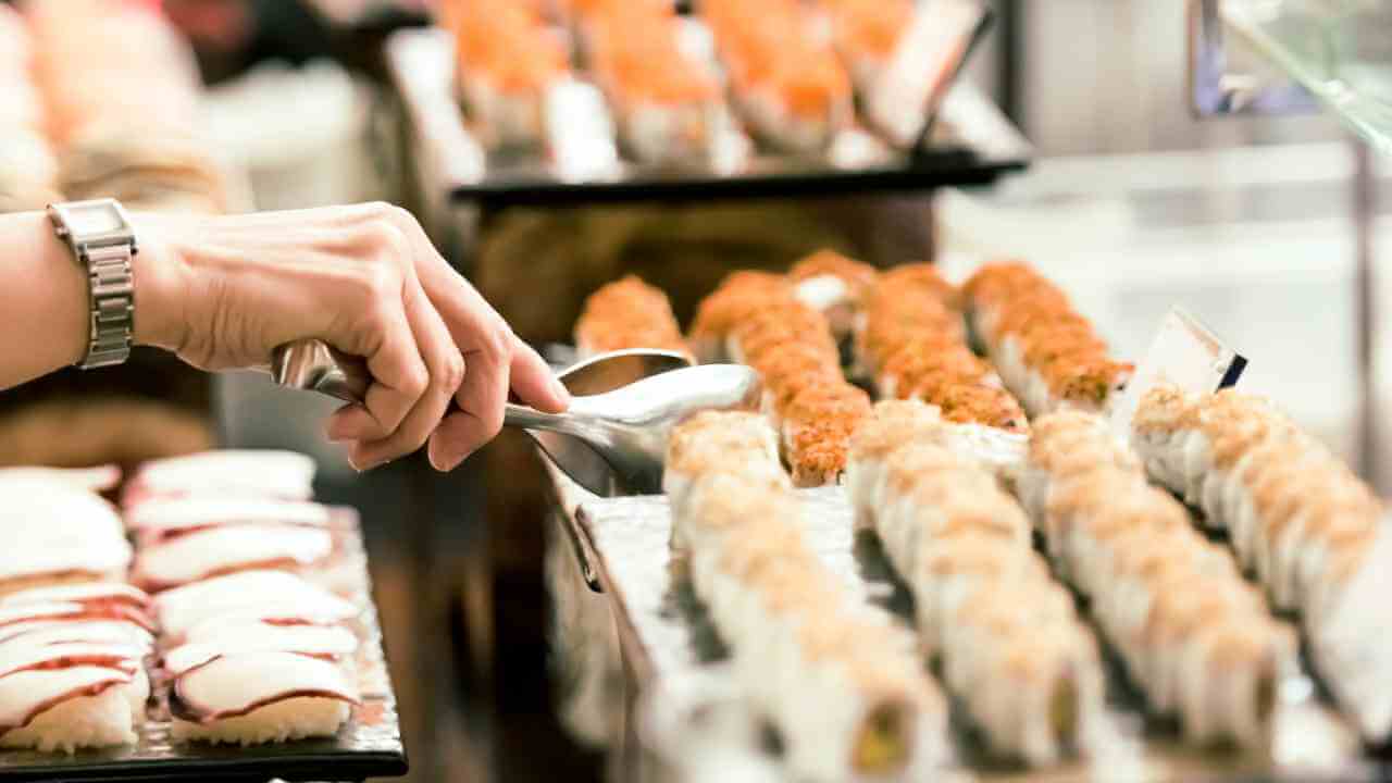 a person is picking up a sushi roll from the counter