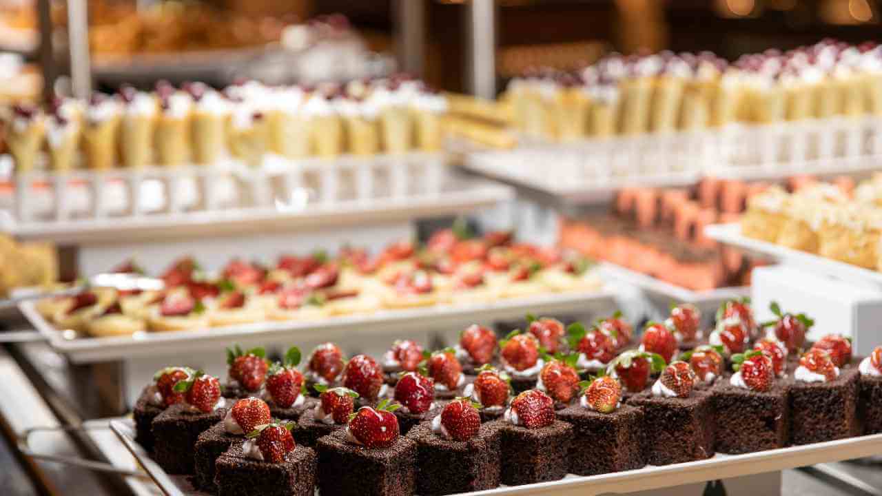 various desserts are displayed on trays in a buffet