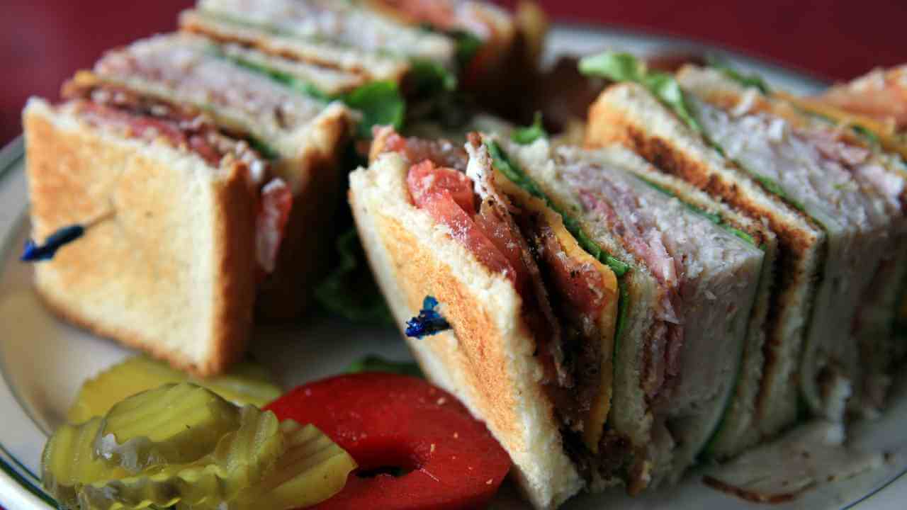 a plate topped with a club sandwich and pickles