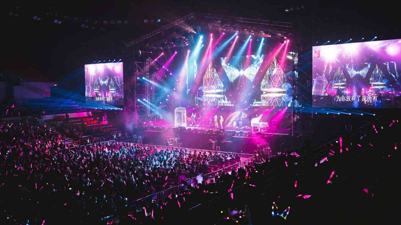 a large crowd at a concert with pink and purple lights