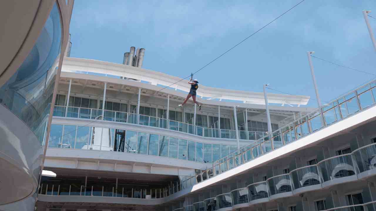 a person on a zipline at the top of a cruise ship