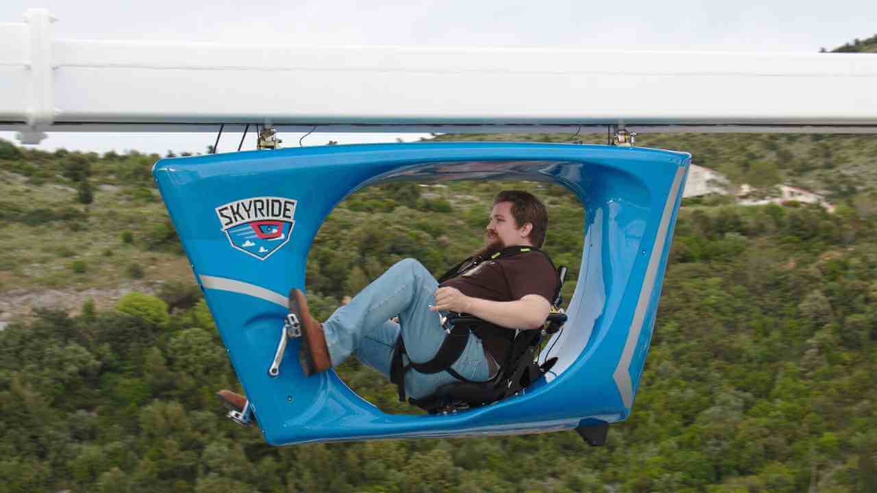 a person sitting in a blue chair on top of a cable car