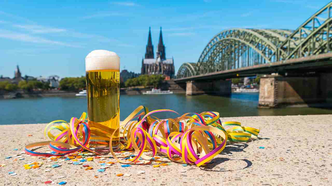 a glass of beer and confetti next to a river with a bridge in the background