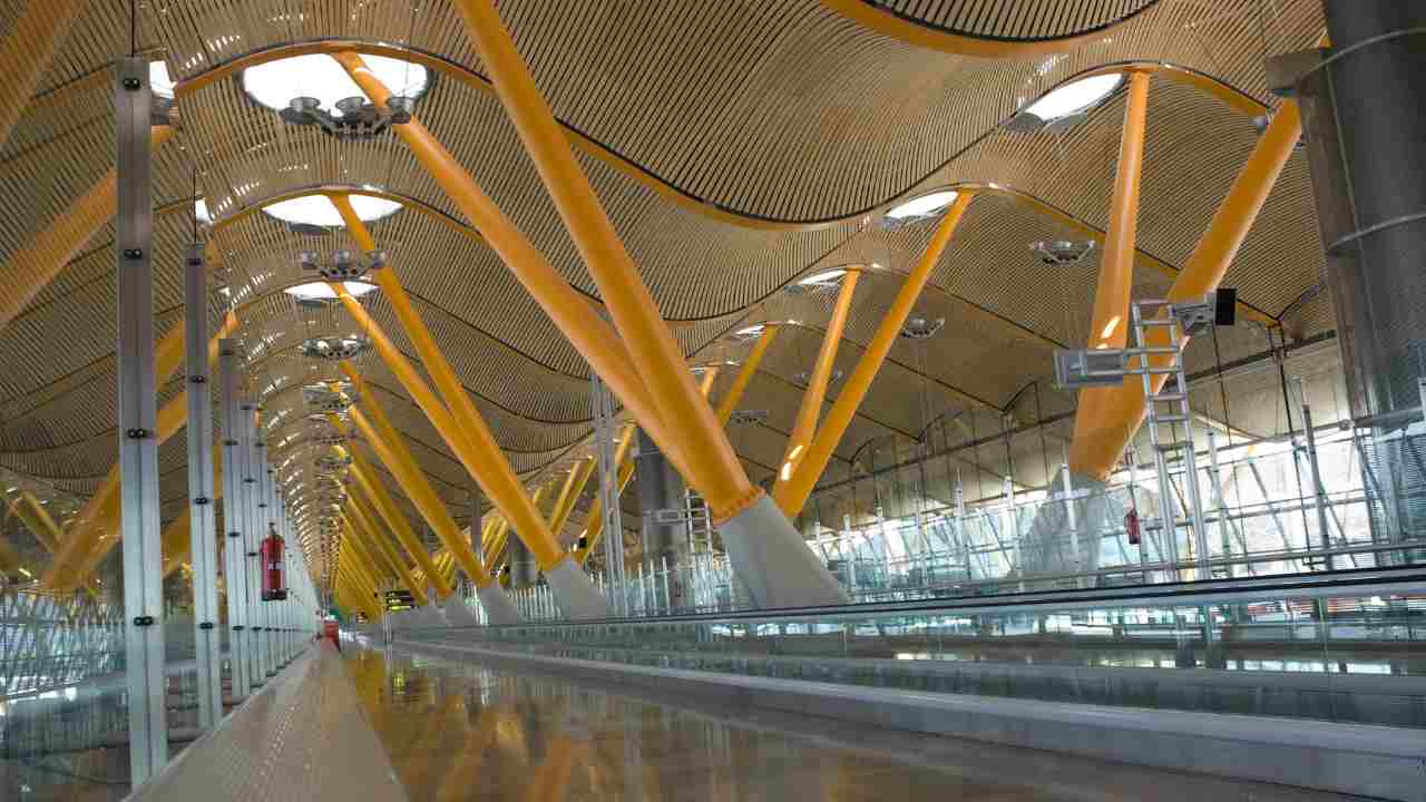 a long walkway in an airport with lots of yellow poles