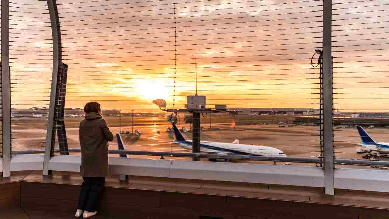 a person looking out over an airport at sunset