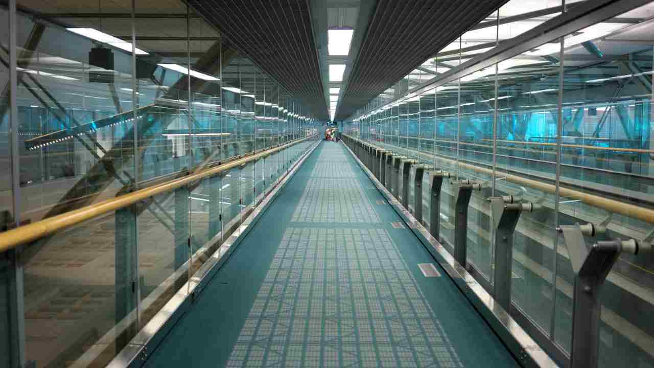 a long walkway in an airport with glass walls