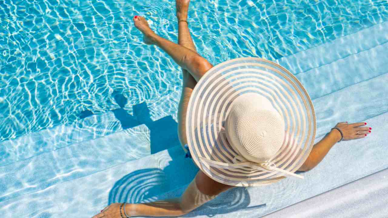 a person in a hat sitting in a pool with their feet in the water