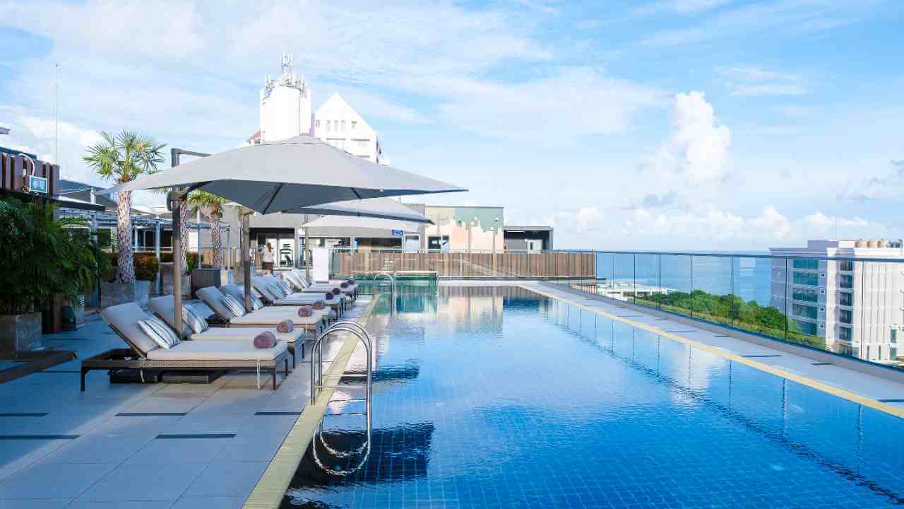an outdoor swimming pool with lounge chairs and umbrellas overlooking the ocean