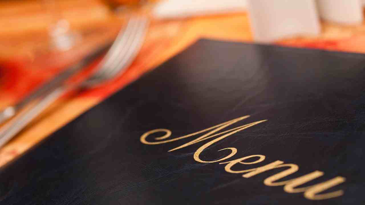 a menu is placed on a table with silverware and wine glasses