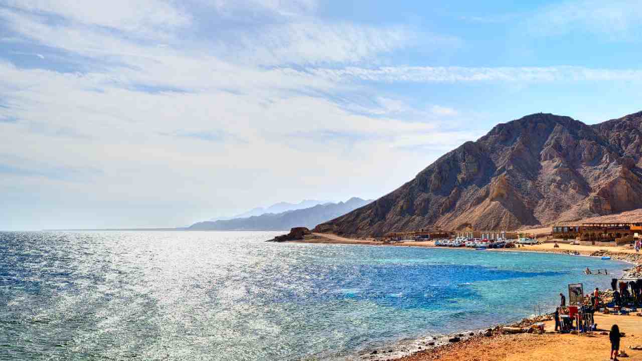 sinai beach in egypt with people on the beach and mountains in the background