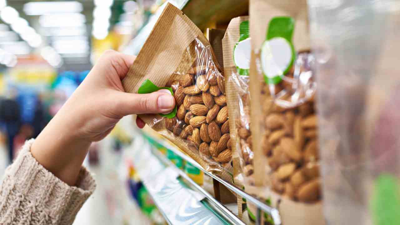 a person is holding a bag of almonds in a grocery store