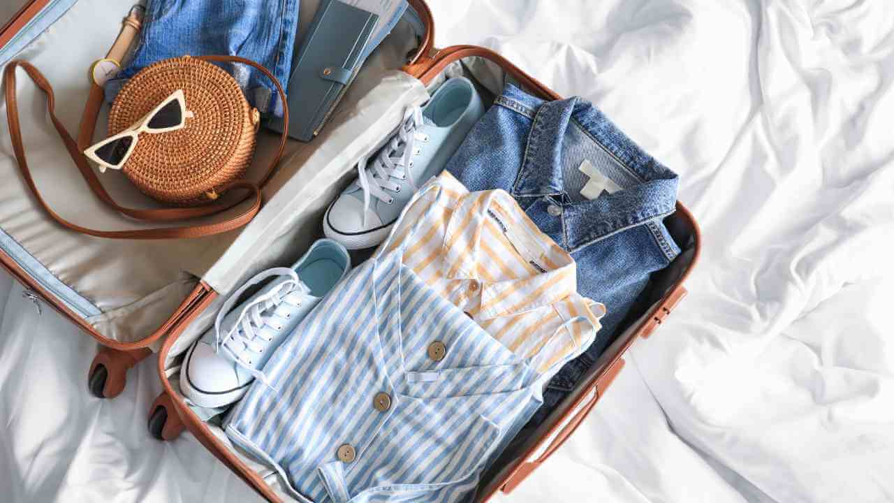 a suitcase filled with clothes and accessories on a bed