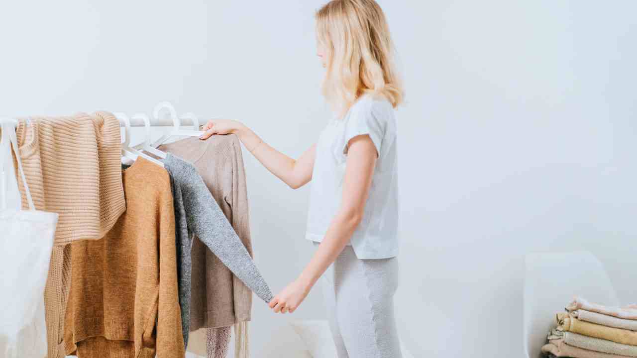 a person is standing in front of a rack of clothes