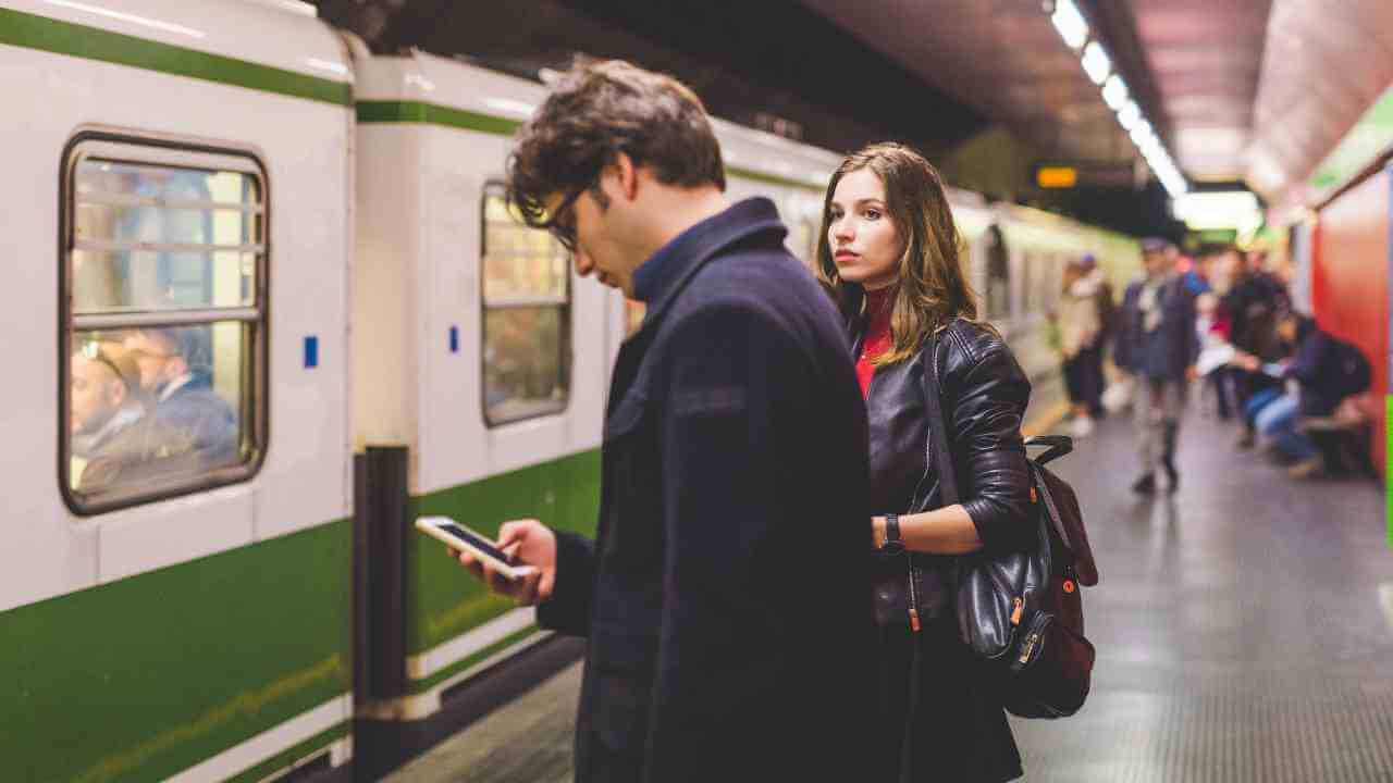 Two people standing next to a subway train