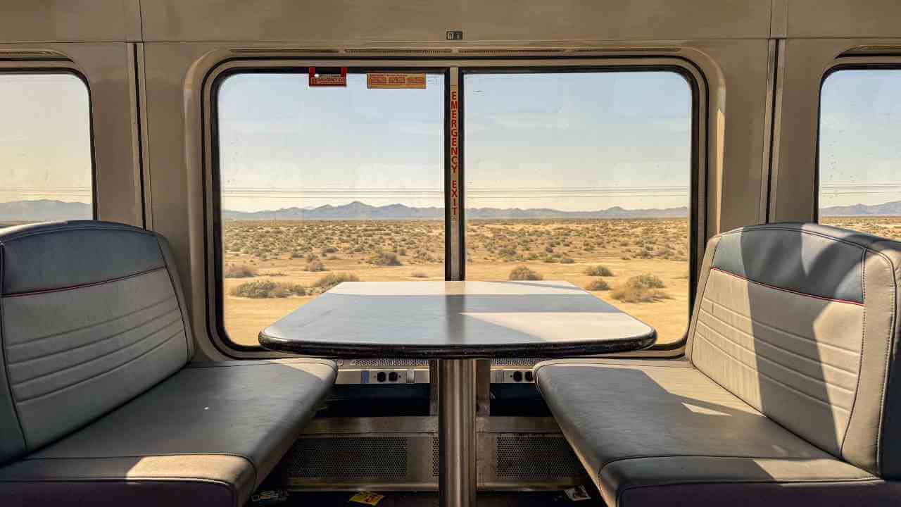 a table and chairs in a train car with a view of the desert