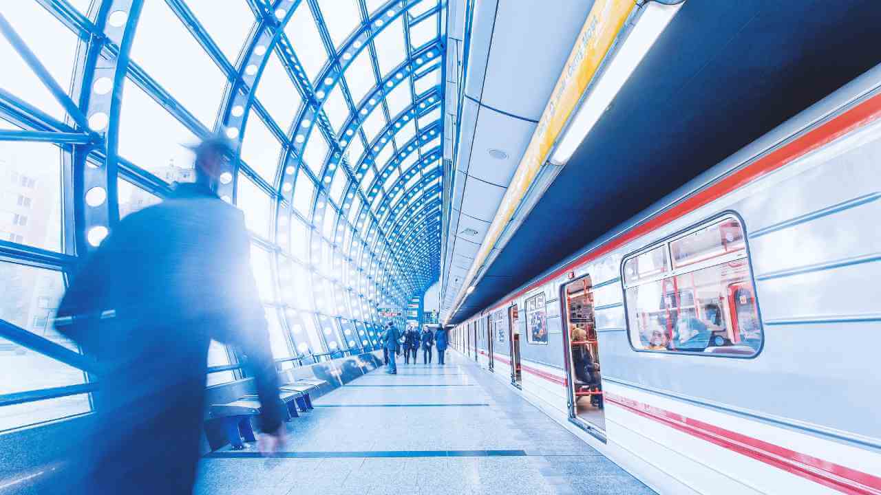 people walking in a subway station with a train in the background