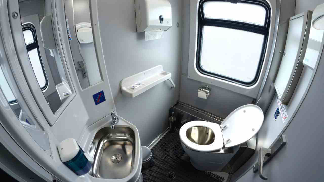 a bathroom with a toilet, sink and mirror