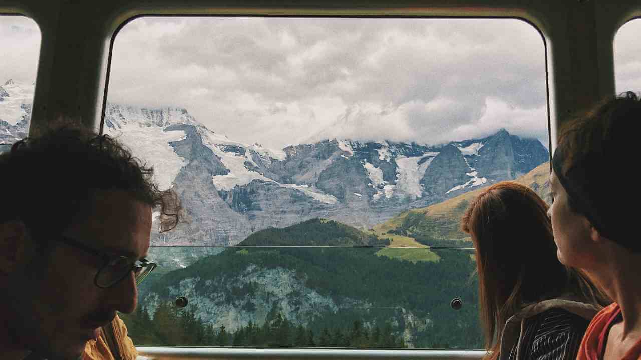 people sitting on a train with mountains in the background