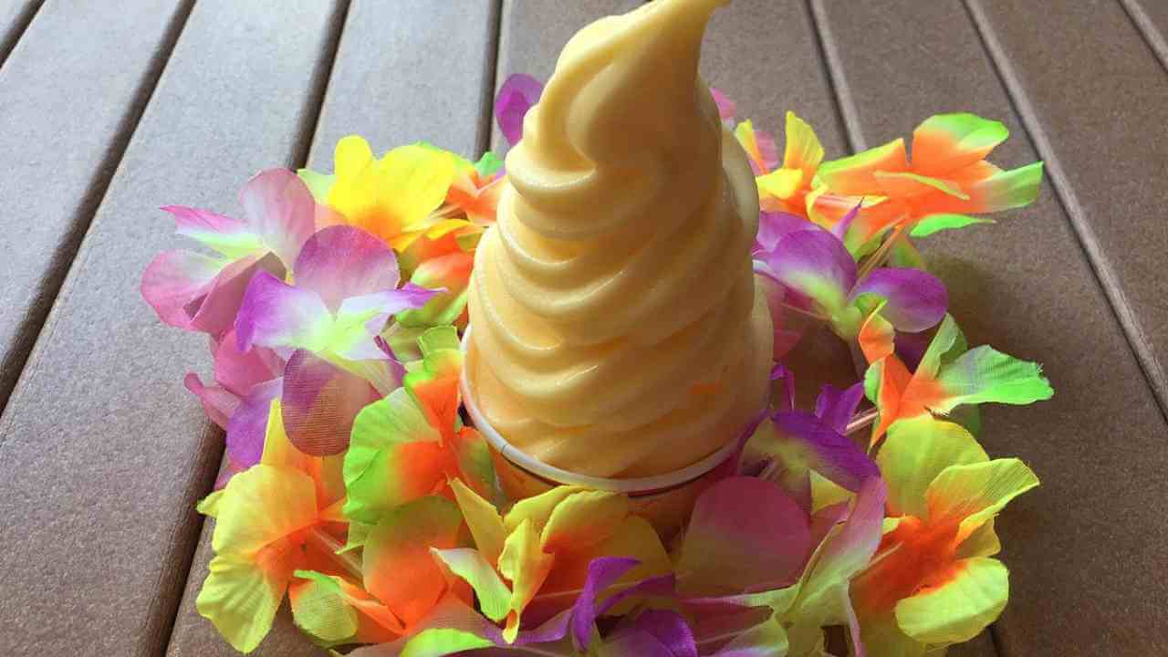 a yellow ice cream cone with flowers on a wooden table