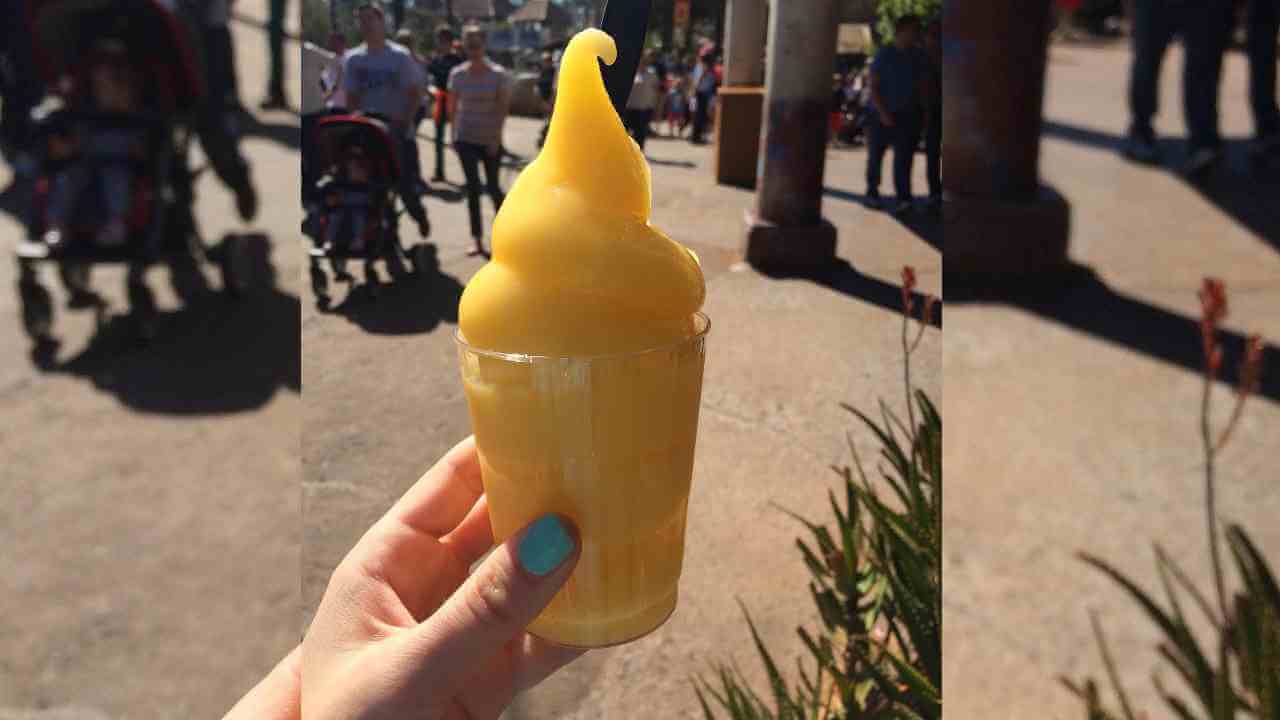 a person holding up a cup of yellow ice cream