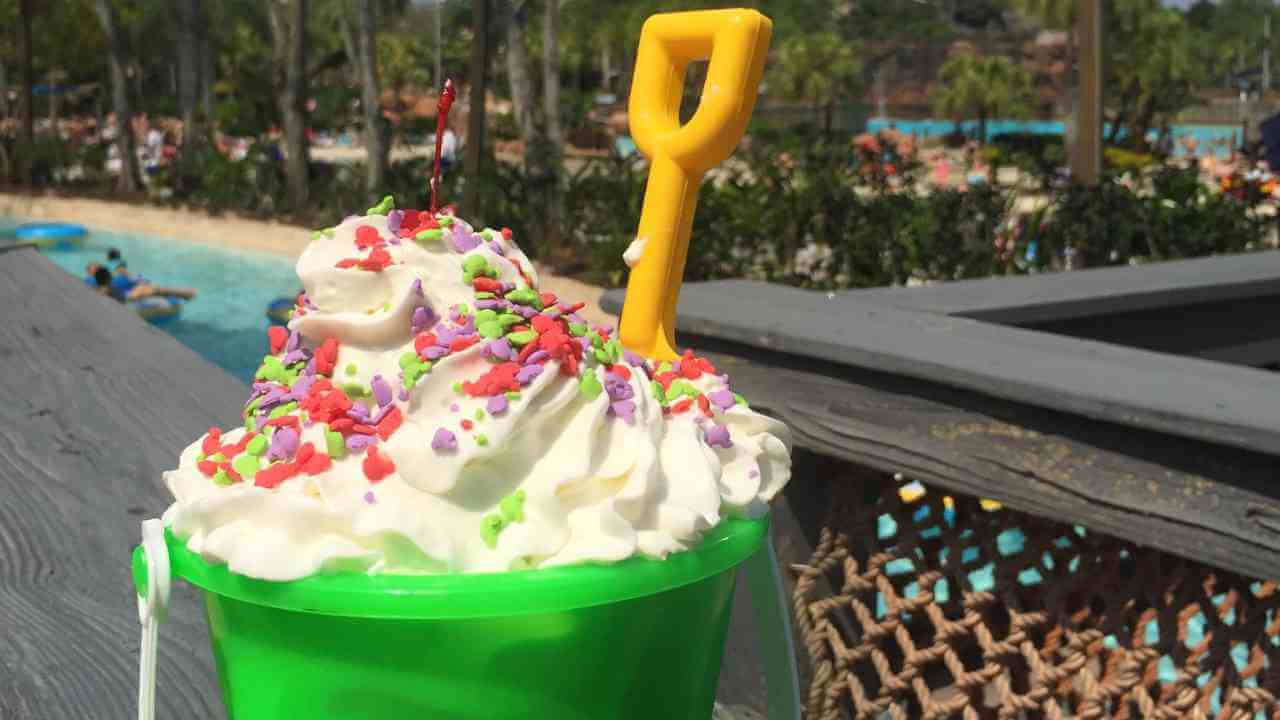 a green bucket filled with whipped cream and sprinkles