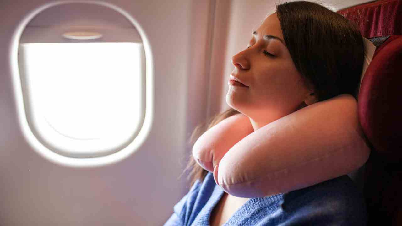 a person is sleeping on an airplane with their eyes closed